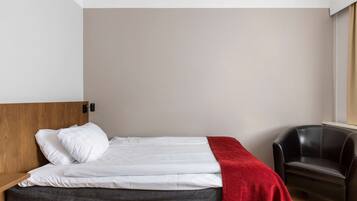 A modern bedroom with a bed, a red throw blanket, a wooden headboard, and a black leather chair.