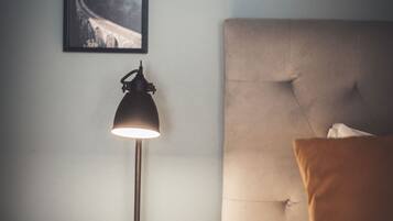 A neatly made bed with a headboard, a bedside lamp, and a framed picture on the wall.