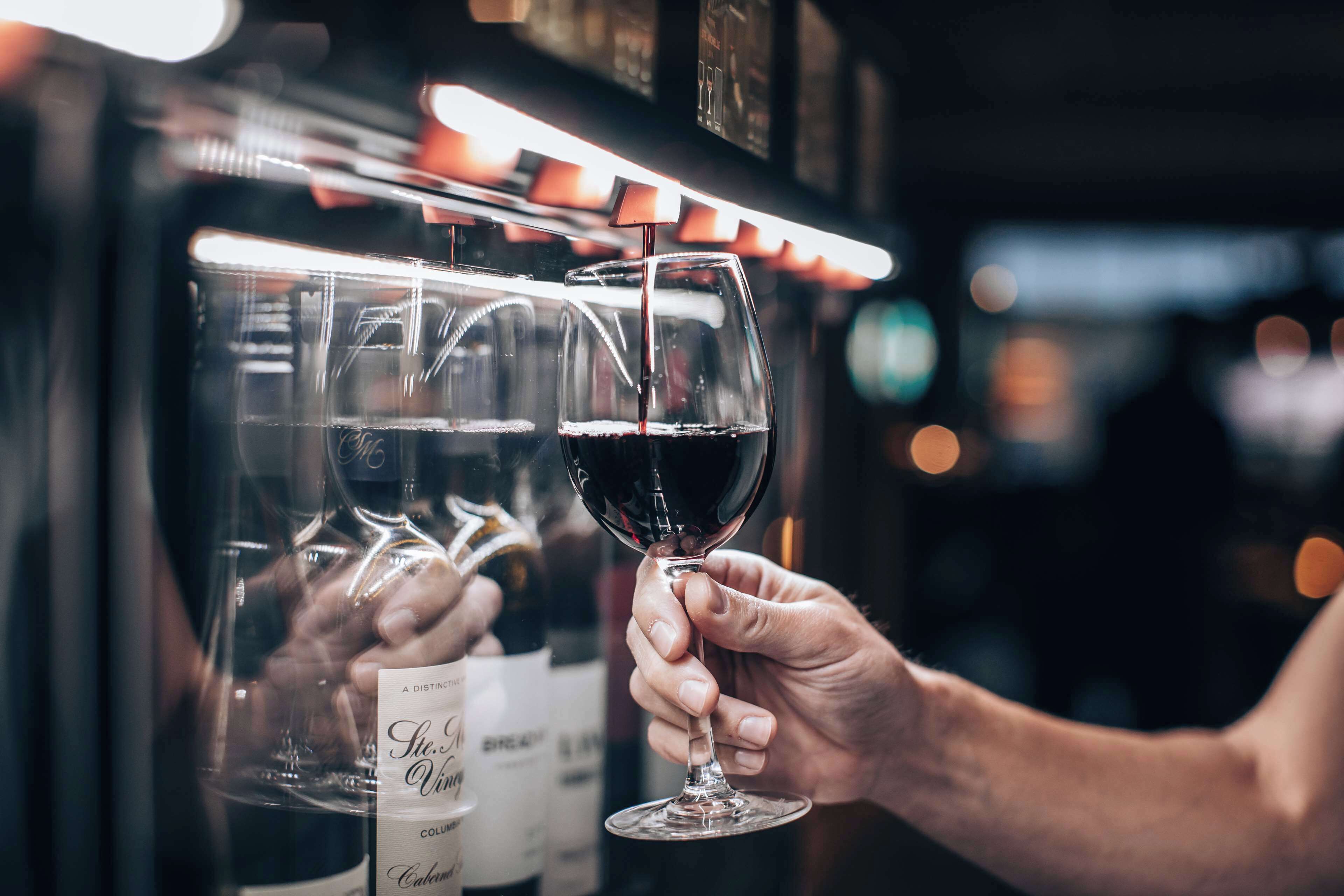 Une personne tenant un verre à vin devant une bouteille de vin.