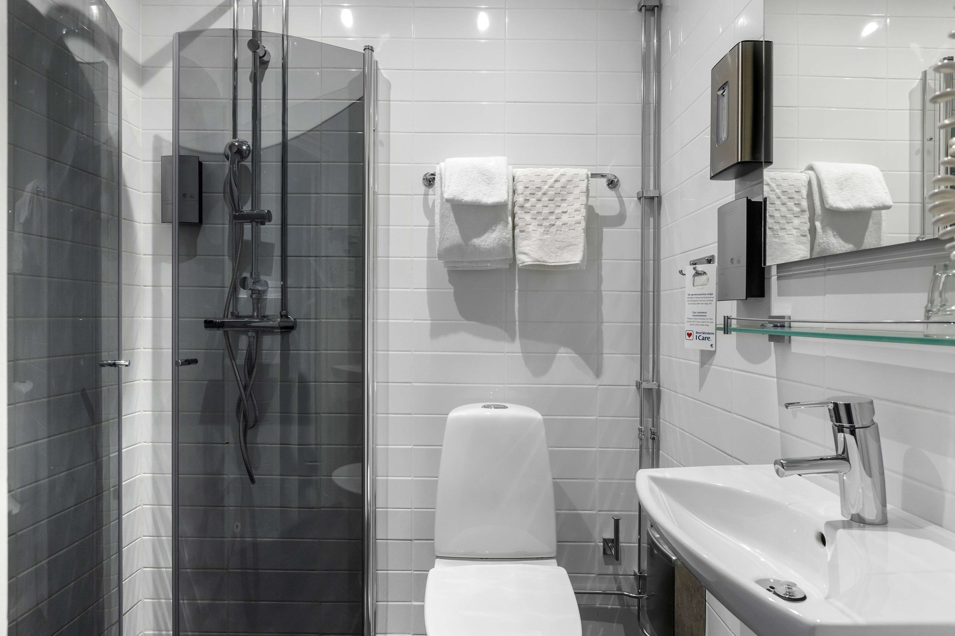Ein modernes Badezimmer mit Duschkabine aus Glas, einer weißen Toilette und einem Waschbecken mit Chromarmatur.