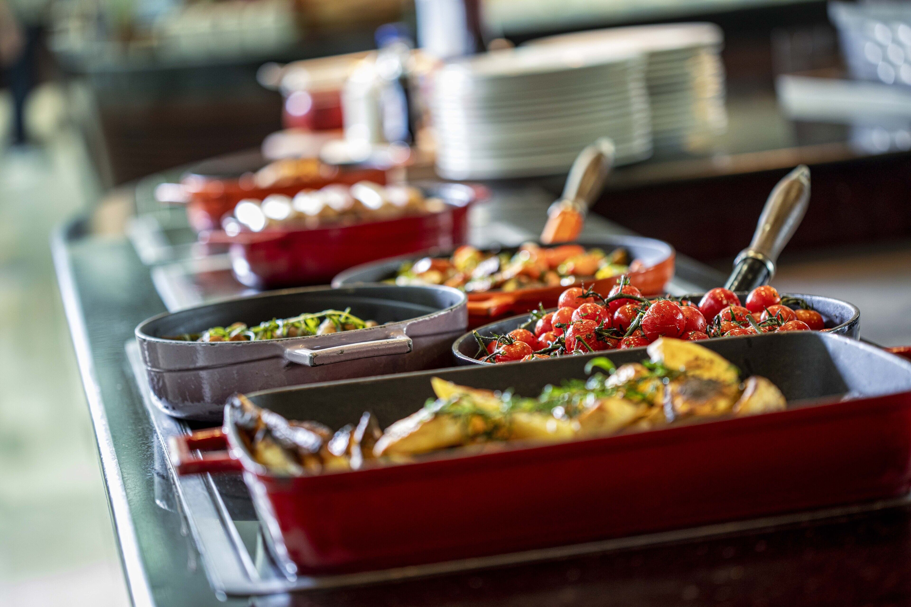 Un buffet proposant divers plats, notamment des légumes rôtis et des salades.