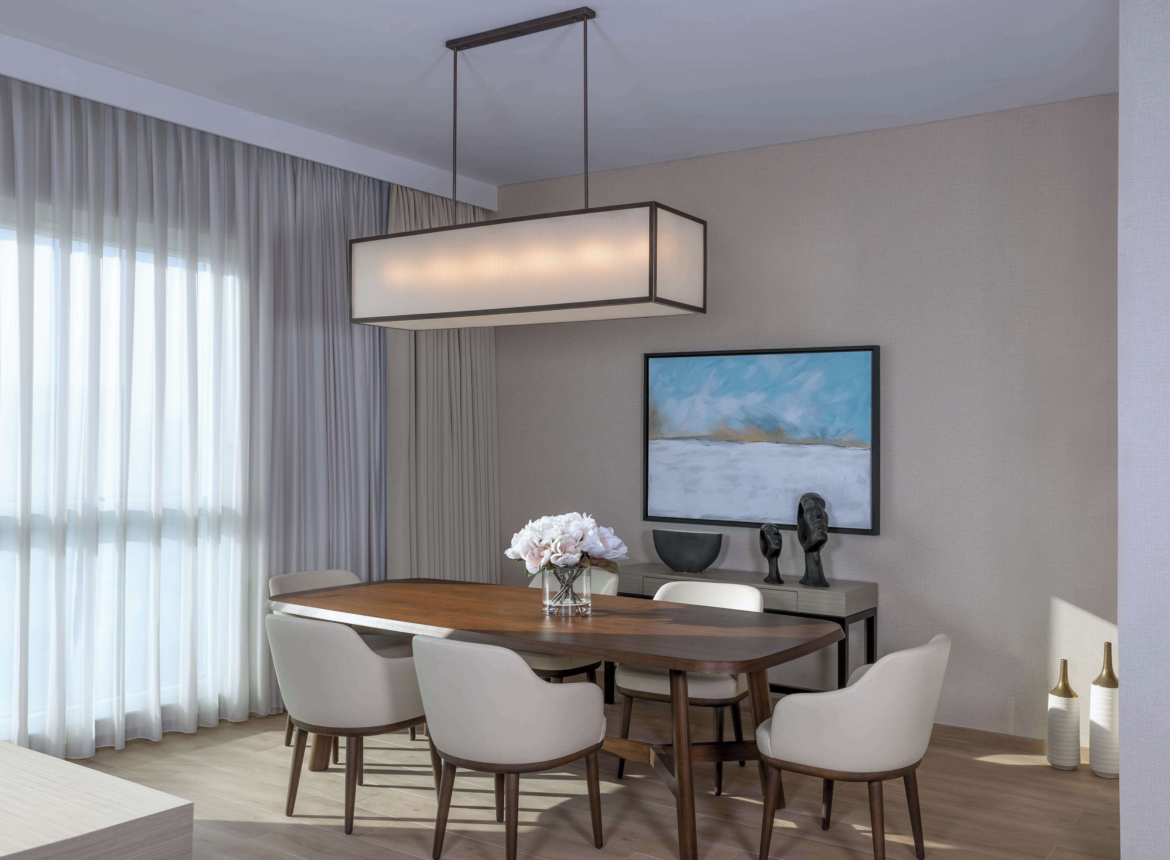 Un comedor moderno con una mesa de madera, seis sillas, un jarrón de flores, un cuadro en la pared y una lámpara colgante.