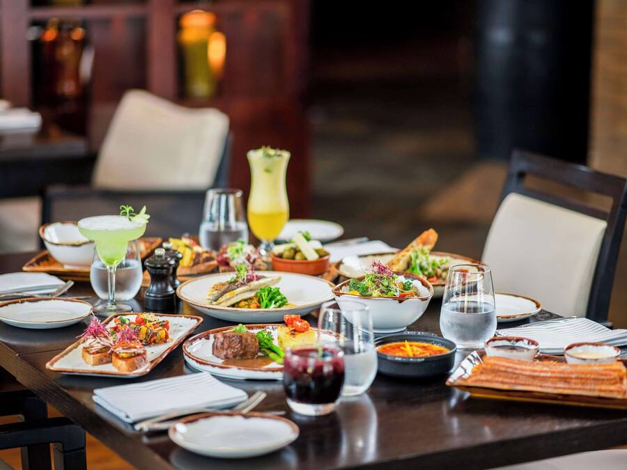Una mesa de comedor bien dispuesta con diferentes platos, vasos y cubiertos.