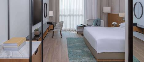 Una habitación de hotel moderna con una cama grande, un escritorio, una silla, un televisor y una ventana con cortinas.