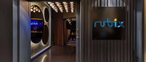 A modern hotel entrance with a 'rubix' sign, a patterned wall, and a wooden floor.