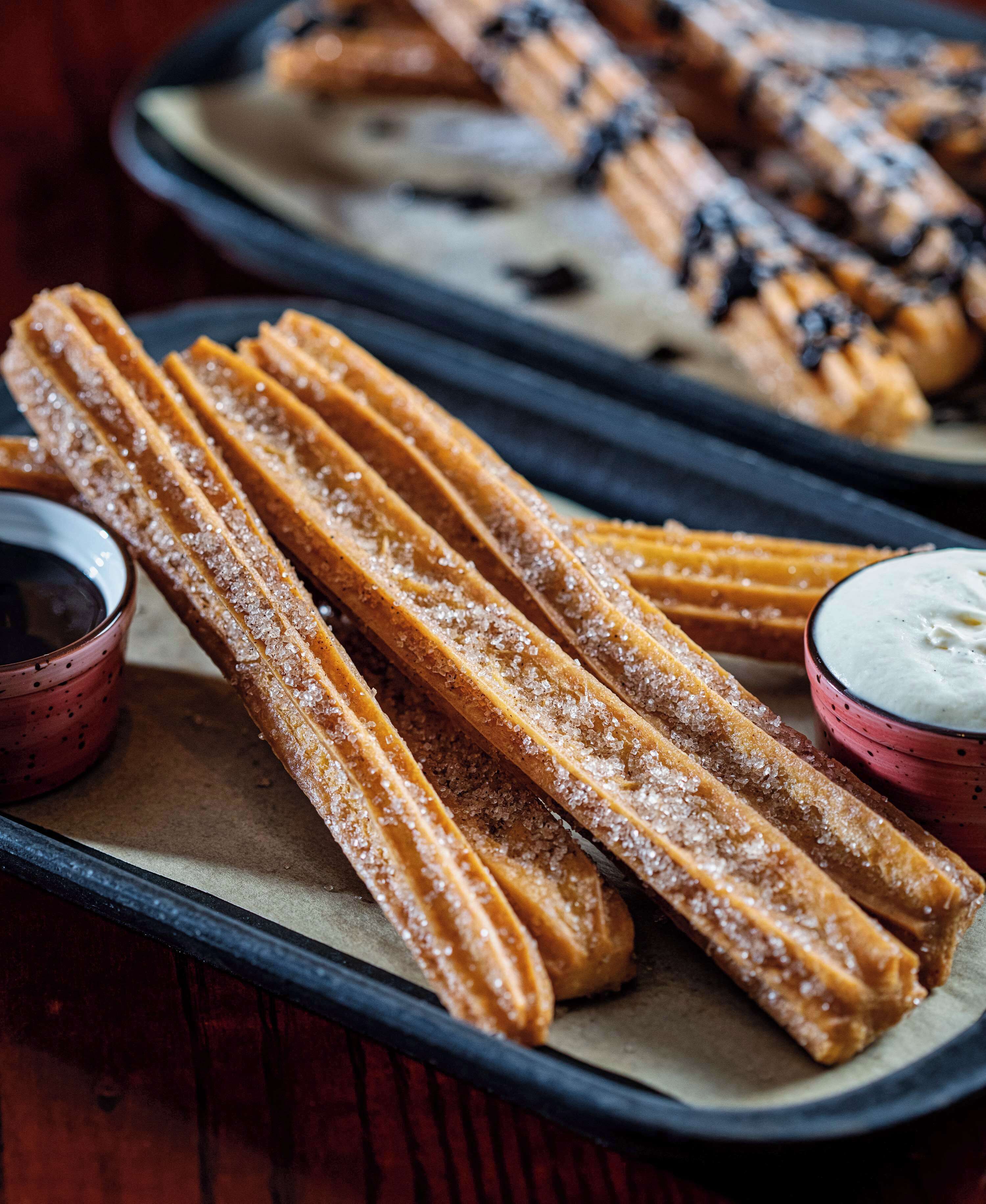 Churros on a tray with dipping sauces.