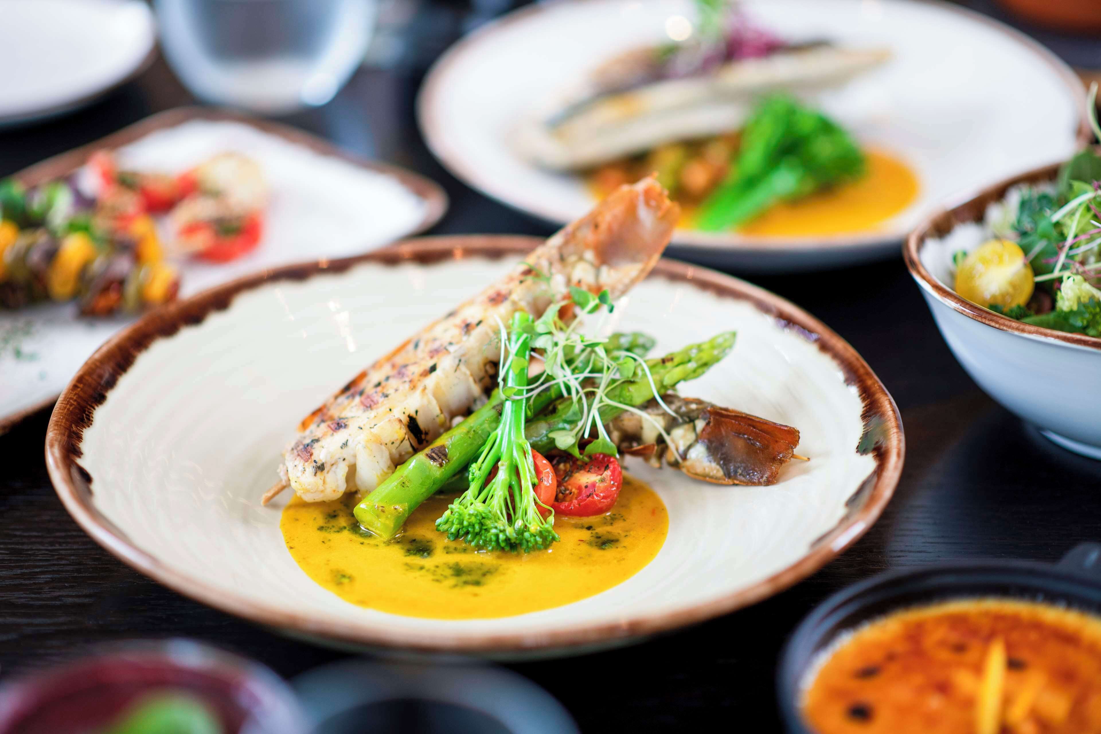 A variety of dishes on plates, including seafood and vegetables, suggesting a dining setting.