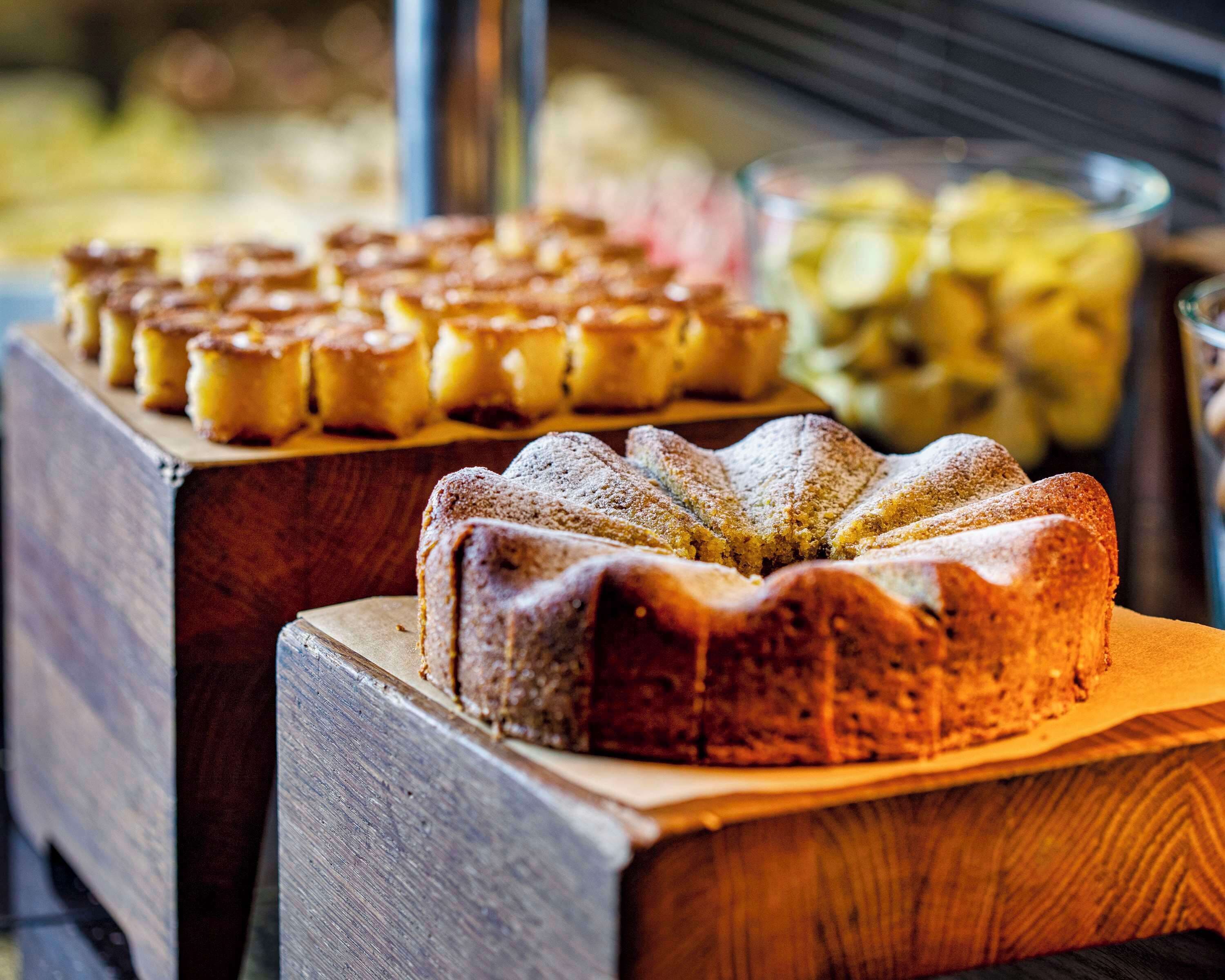 A wooden display with various baked goods, including a bundt cake and several smaller pastries.