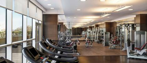 Un gimnasio con cintas de correr, máquinas de pesas y espejos.
