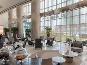 Un'ampia hall con arredamento moderno, grandi finestre e piante da interno.