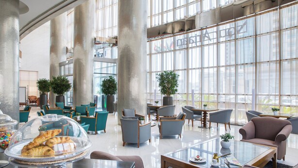 A spacious lobby with high ceilings, large windows, and modern furniture.