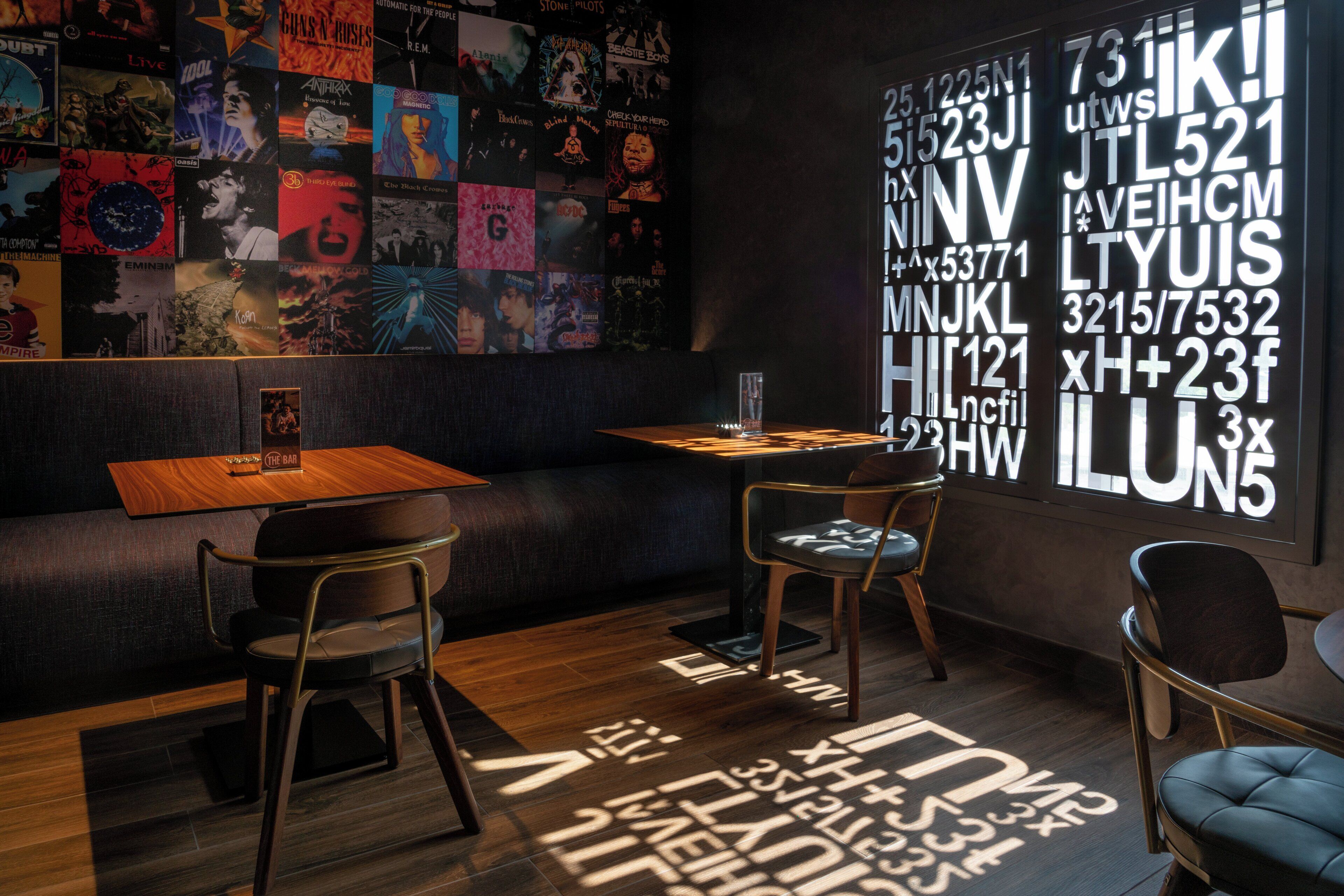 Un interior moderno con una pared de portadas de discos, una mesa de madera y dos sillas.