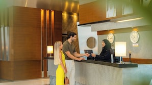 A reception area with a reception desk, clocks, and a wall-mounted lamp.