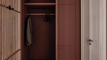 A walk-in closet with a hanging rod, a suitcase, and a door.