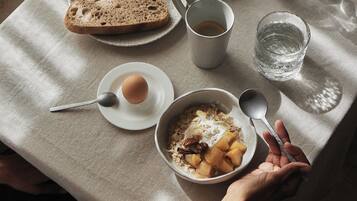 A breakfast table with toast, eggs, fruit, and a cup of coffee.