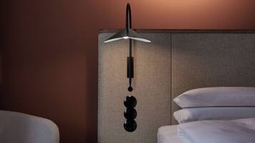 Un dormitorio moderno con una cama, una lámpara de pared redonda, una mesita de noche de madera y una silla.