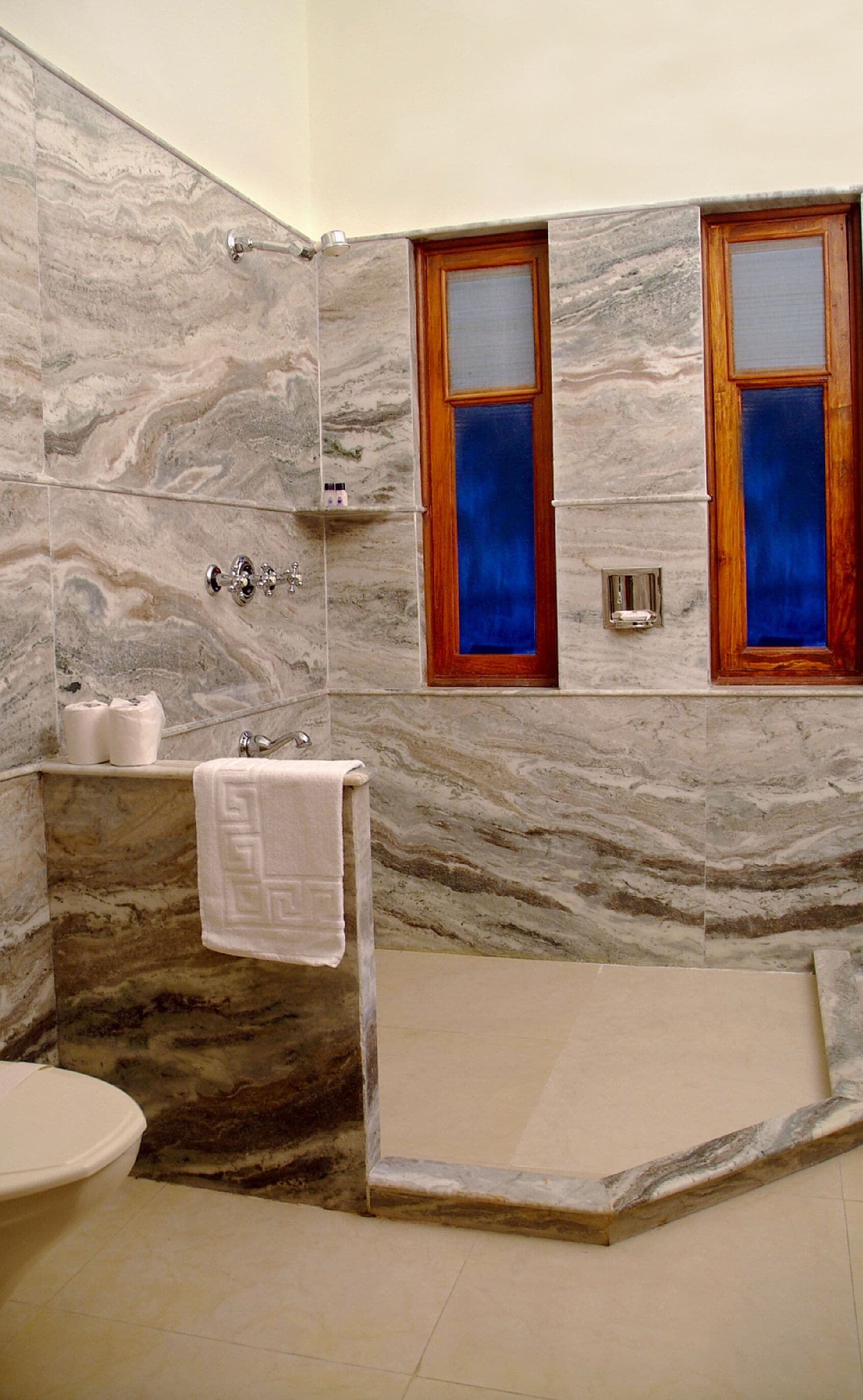 Ein Badezimmer mit Marmorwänden, einer Badewanne, einer Dusche und einem WC.
