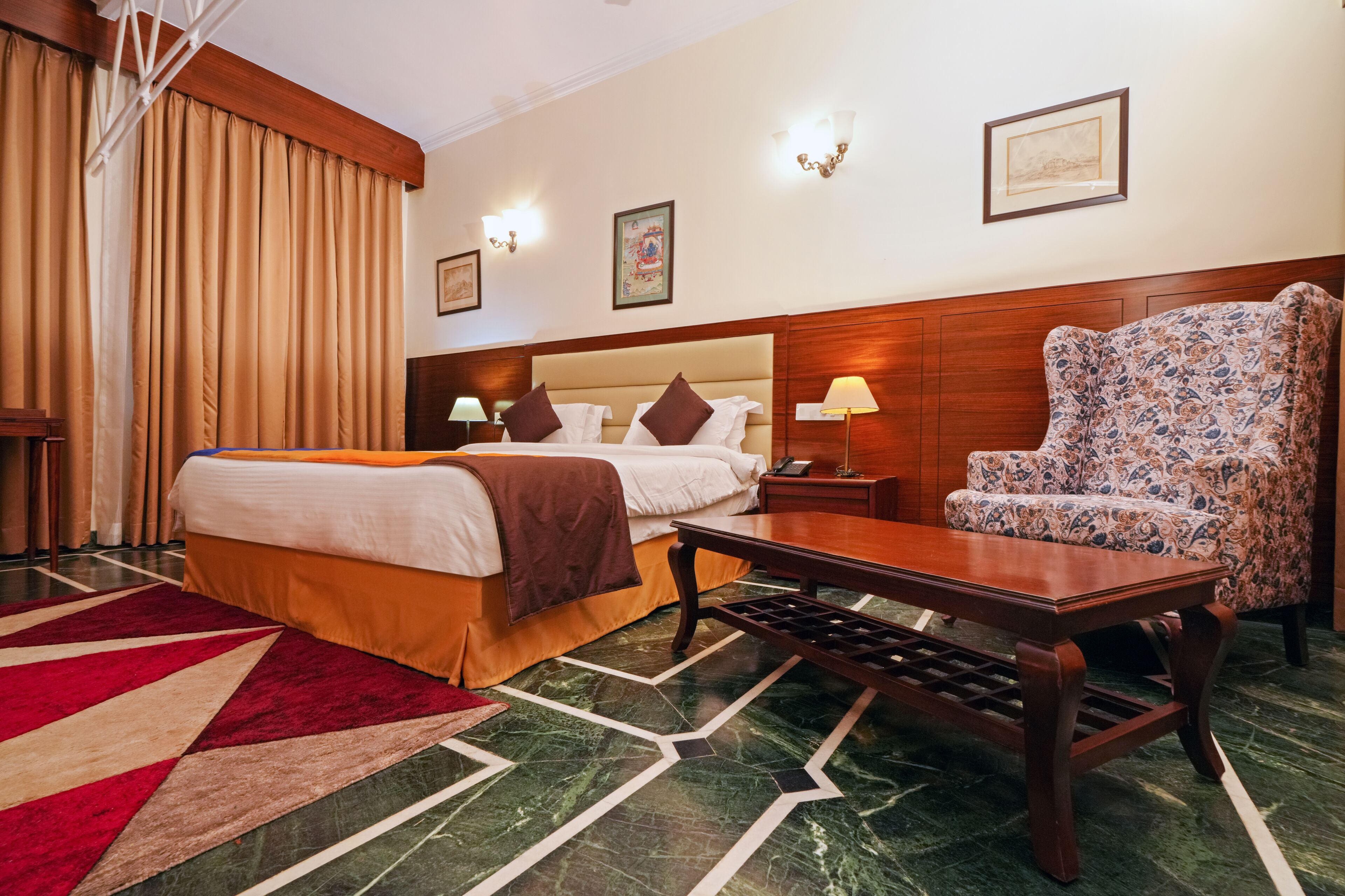 A hotel room with a bed, a chair, a nightstand, and a table.