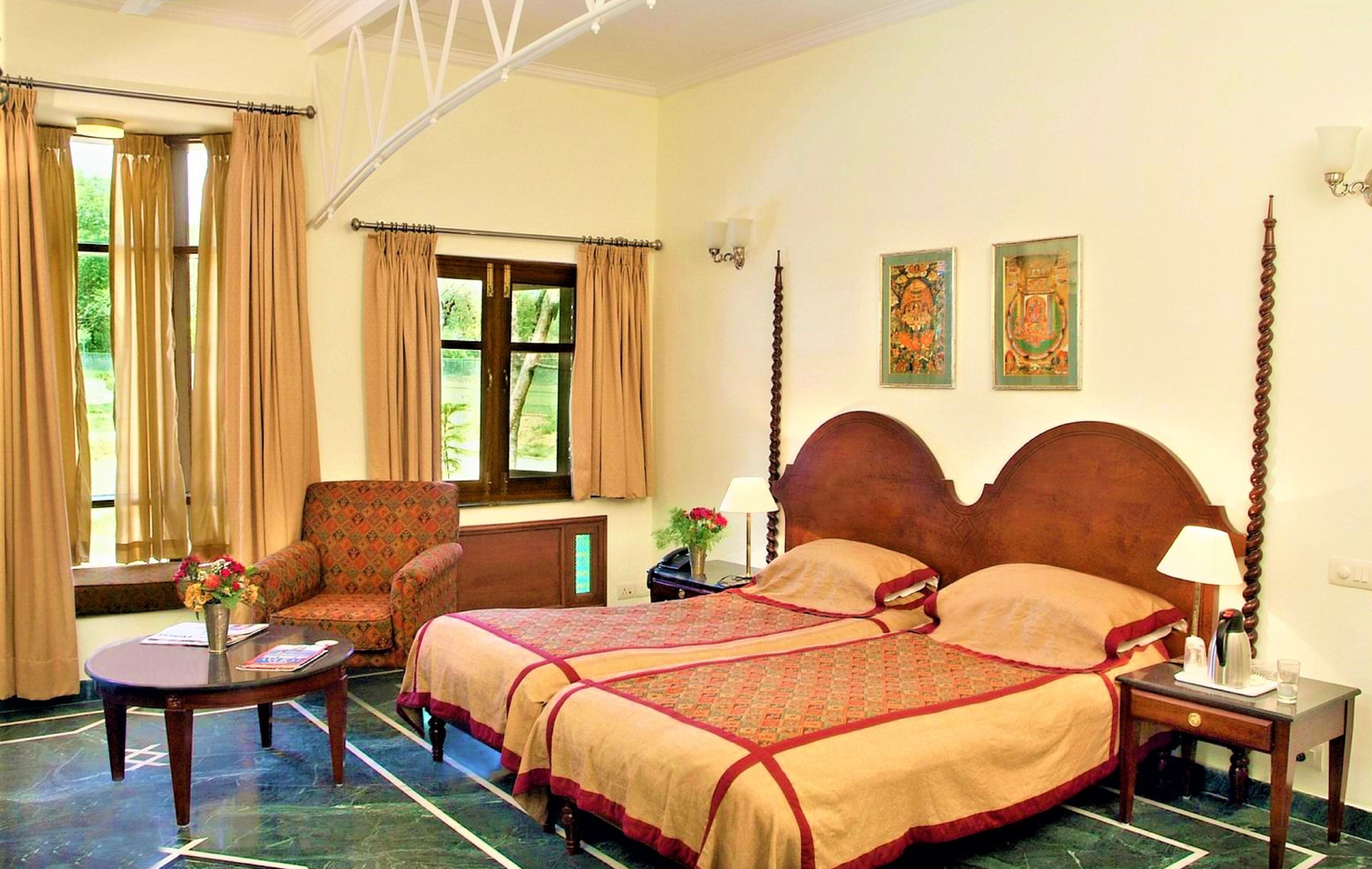A hotel room with a large bed, a chair, a small table, and a window with curtains.