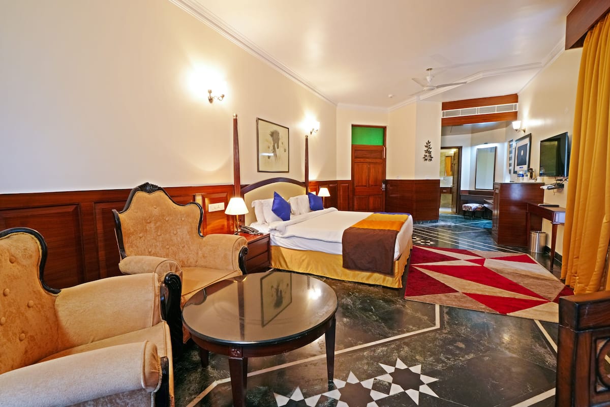 Een hotelkamer met een bed, een bank, een tafel en een spiegel.