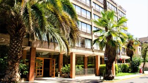 Un hotel con fachada moderna, amplias ventanas y palmeras al frente.