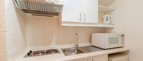 A kitchen with a microwave, sink, stove, and cabinets.