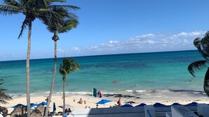 A beach with palm trees, clear blue water, and a flag. - Pelicano Inn Playa del Carmen - Beachfront Hotel (Playa del Carmen)