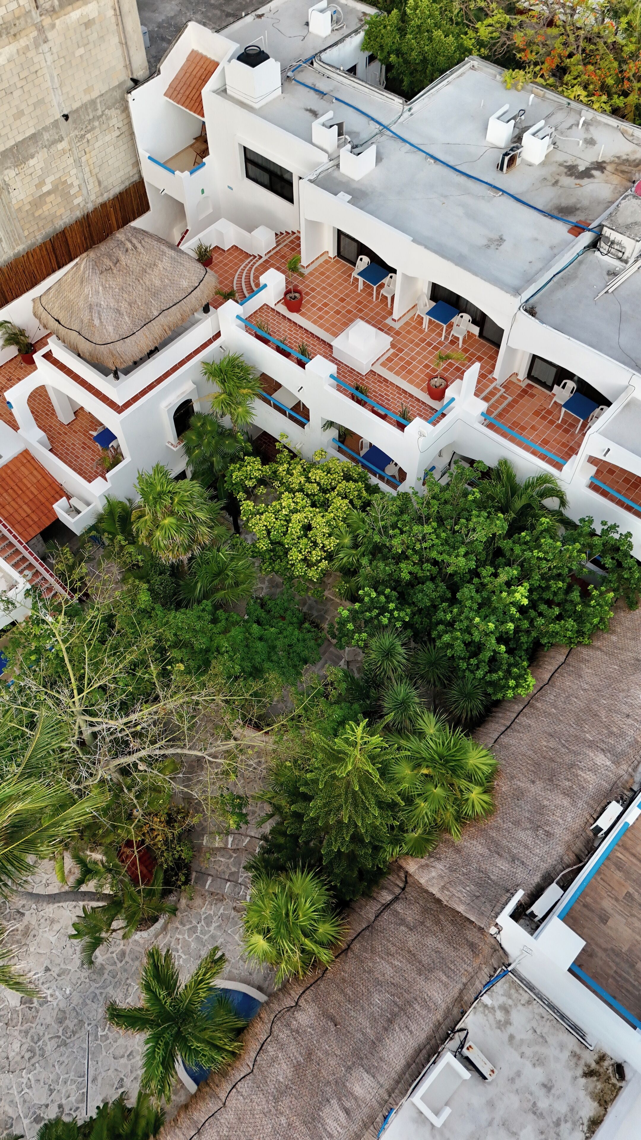 Vue aérienne d’un immeuble résidentiel doté de nombreux balcons, d’un jardin sur le toit et entouré de verdure.