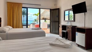 A hotel room with two beds, a desk, a TV, and a view of the ocean. - Pelicano Inn Playa del Carmen - Beachfront Hotel (Playa del Carmen)