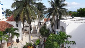 A white building with a tiled roof, palm trees, and a staircase leading to a higher level. - Pelicano Inn Playa del Carmen - Beachfront Hotel (Playa del Carmen)