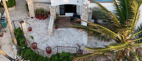 A white building with a thatched roof, multiple balconies, and a pool area.