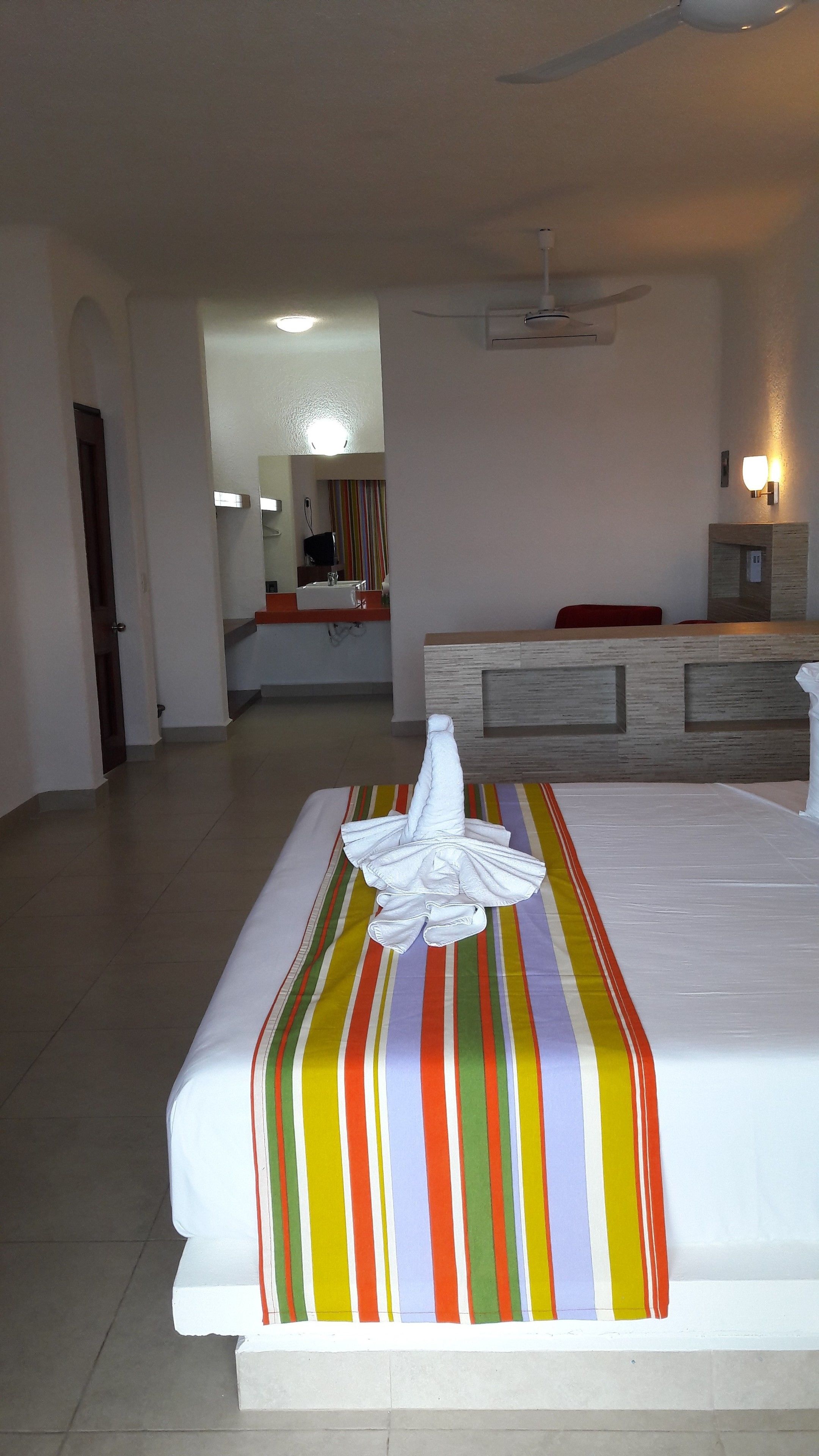 A hotel room with a bed, a desk, and a bathroom visible in the background.