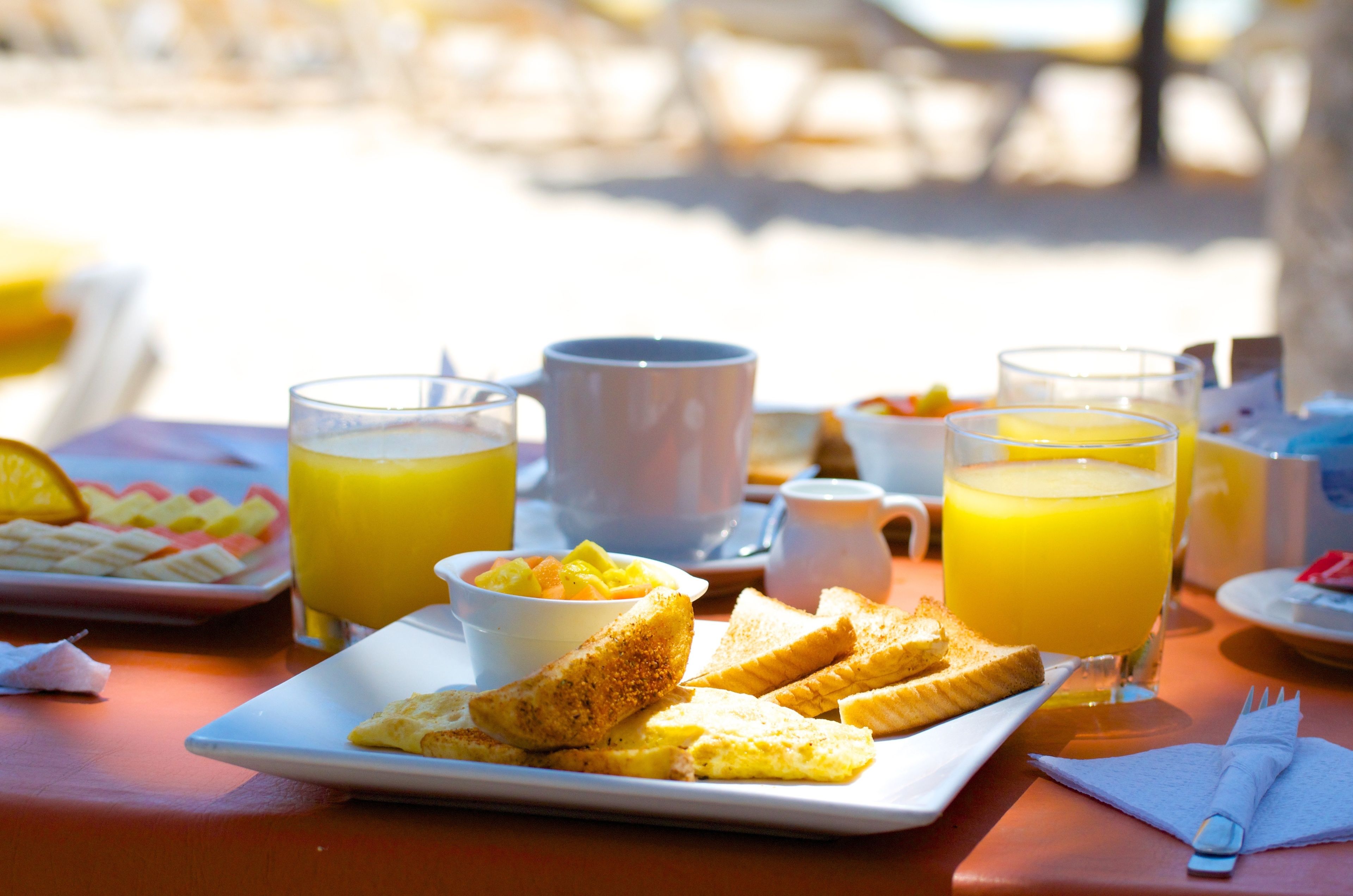 Ein Frühstückstisch mit Toast, Orangensaft und einer Obstschale.
