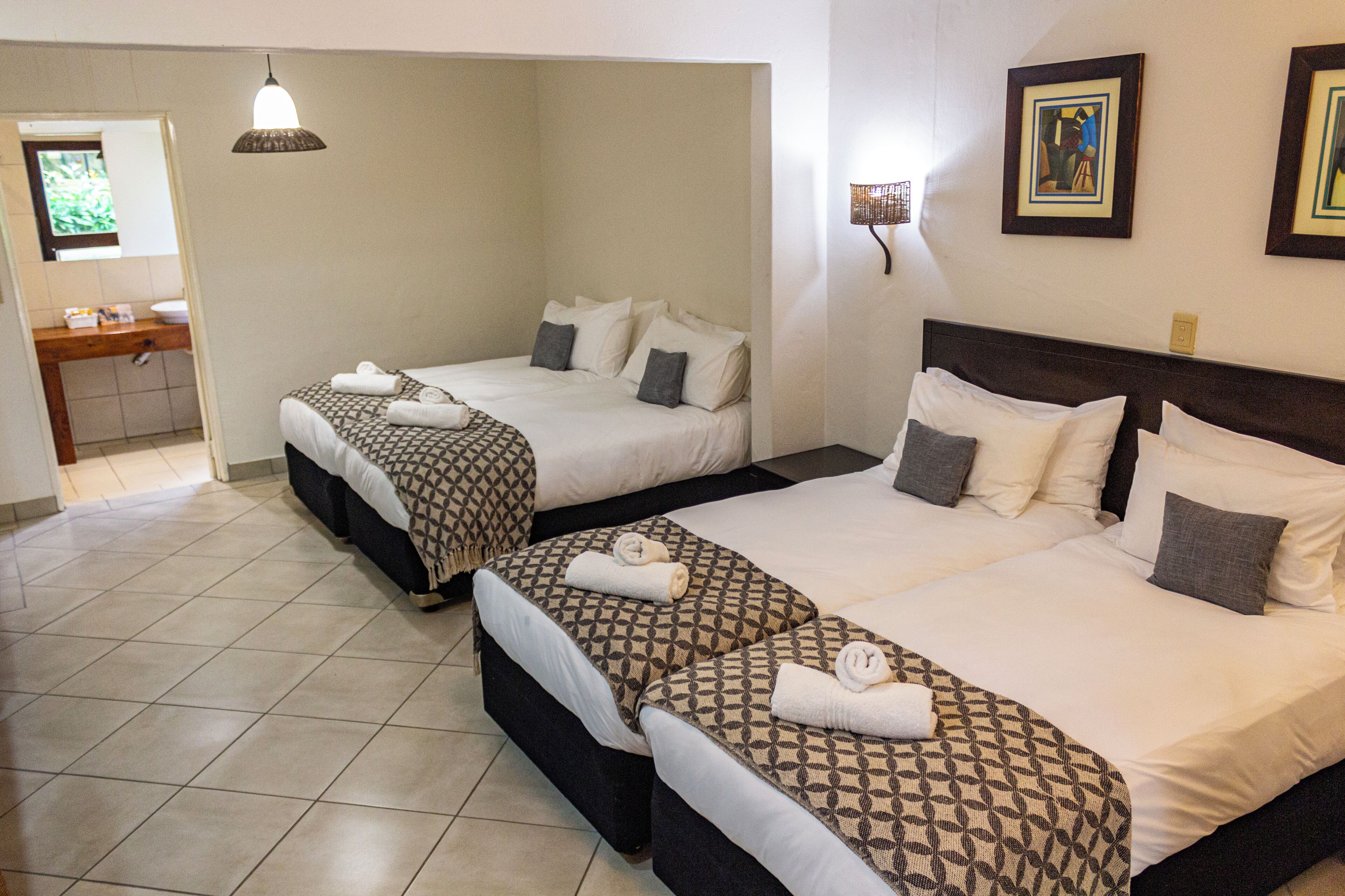 A hotel room with two beds, a bathroom, and a small sitting area.