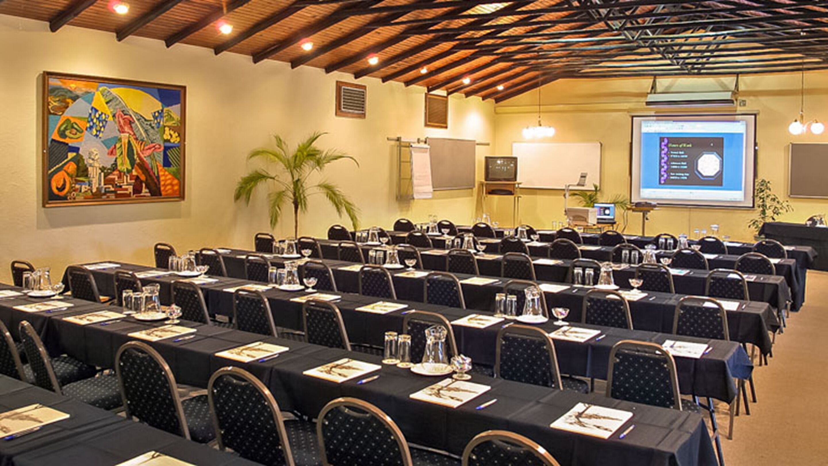 A conference room with rows of tables, chairs, and presentation screens.