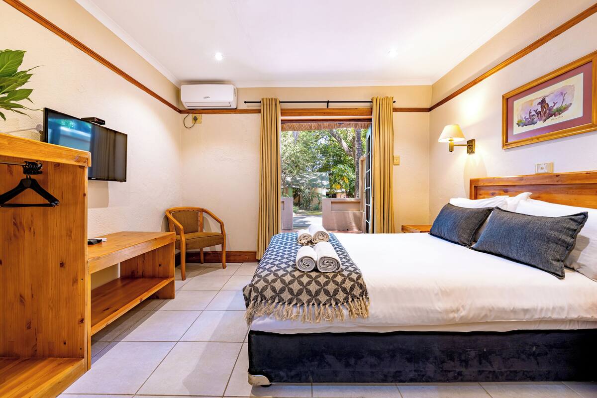 Une chambre d’hôtel avec un lit, une télévision, un bureau et une chaise.