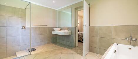 A modern bathroom with a walk-in shower, a freestanding bathtub, and a vanity with a mirror.