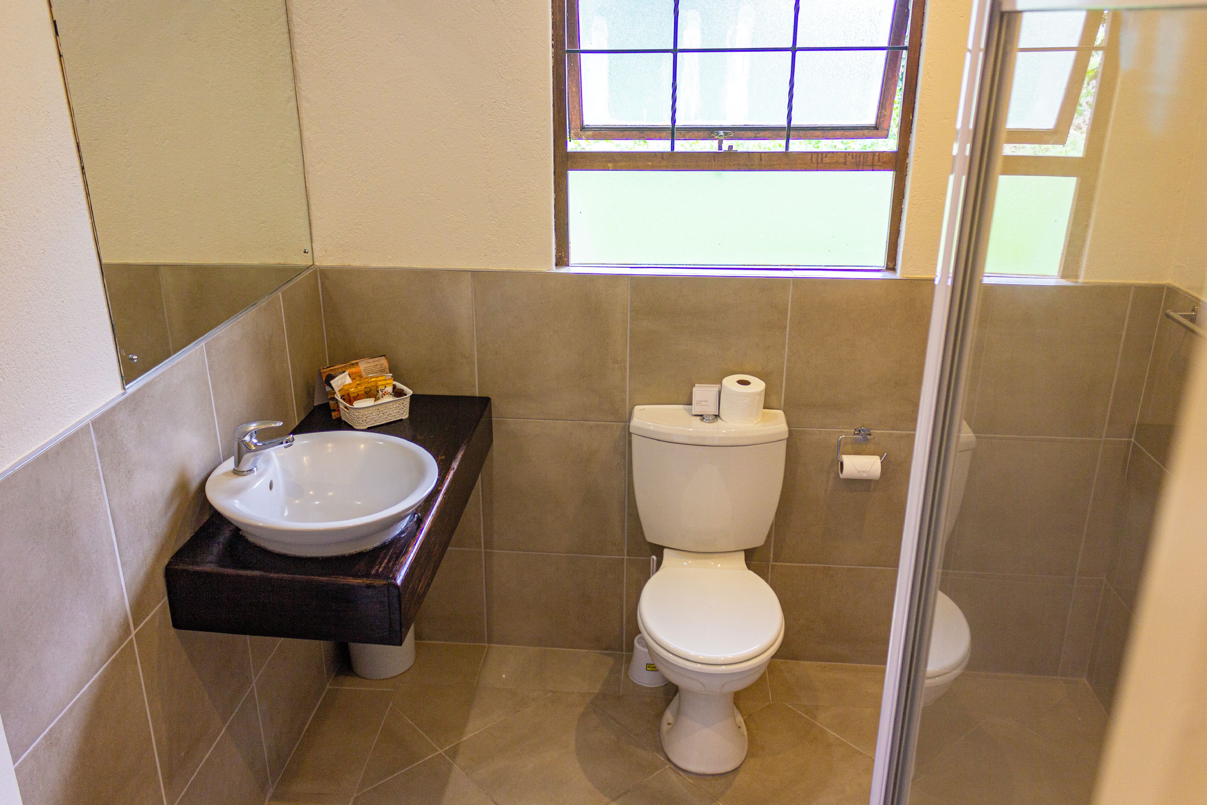 Un baño con lavamanos blanco, inodoro y una pequeña ventana.