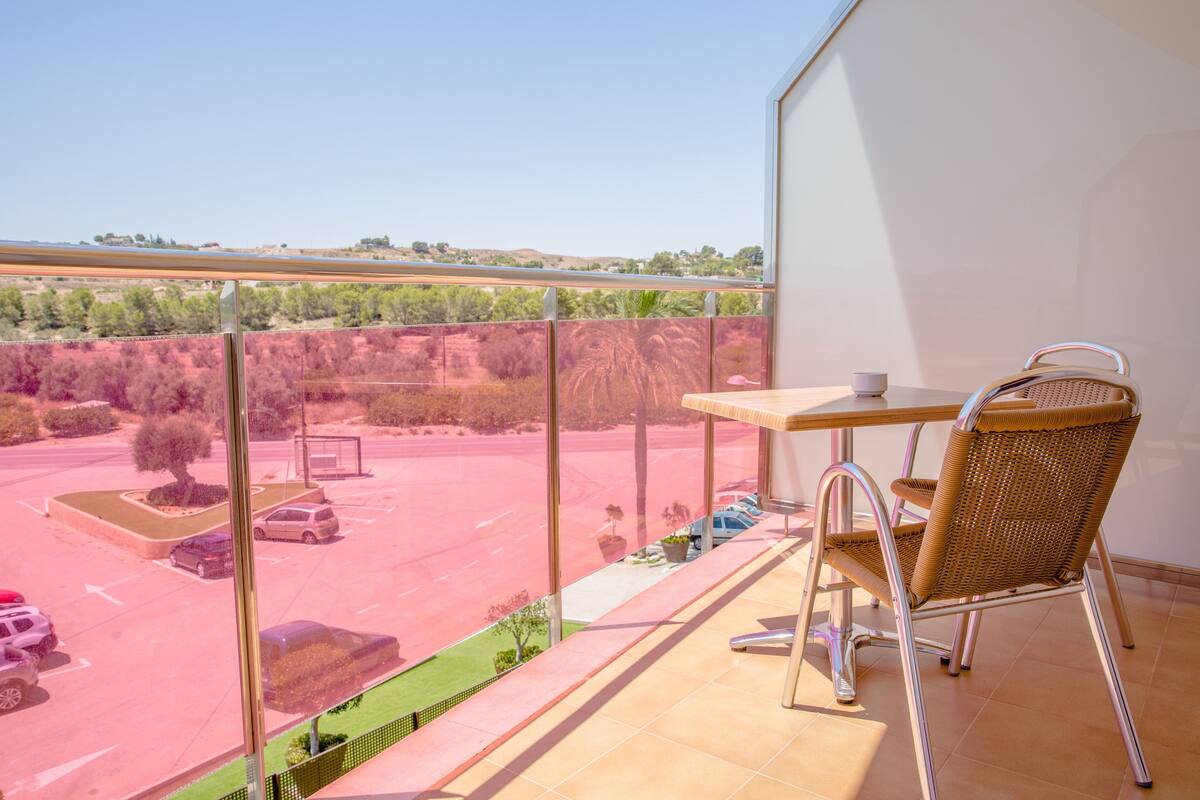 A balcony with a view of a parking lot and distant landscape.