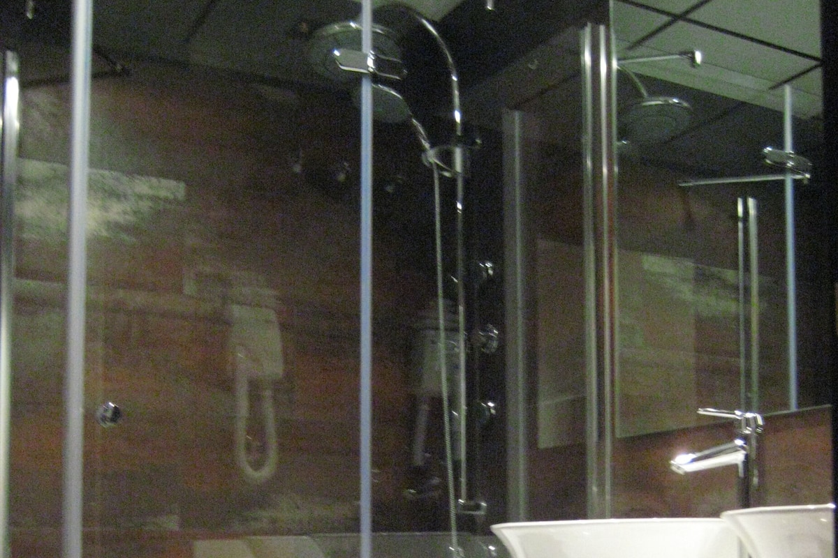 A modern bathroom with a glass-enclosed shower, a white sink, and two towels hanging on a rack.