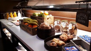 Ein Buffet mit verschiedenen Speisen, darunter Obst, Kekse und Gebäck.