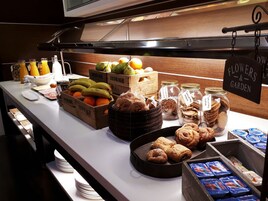 A buffet with various food items including fruits, cookies, and pastries.