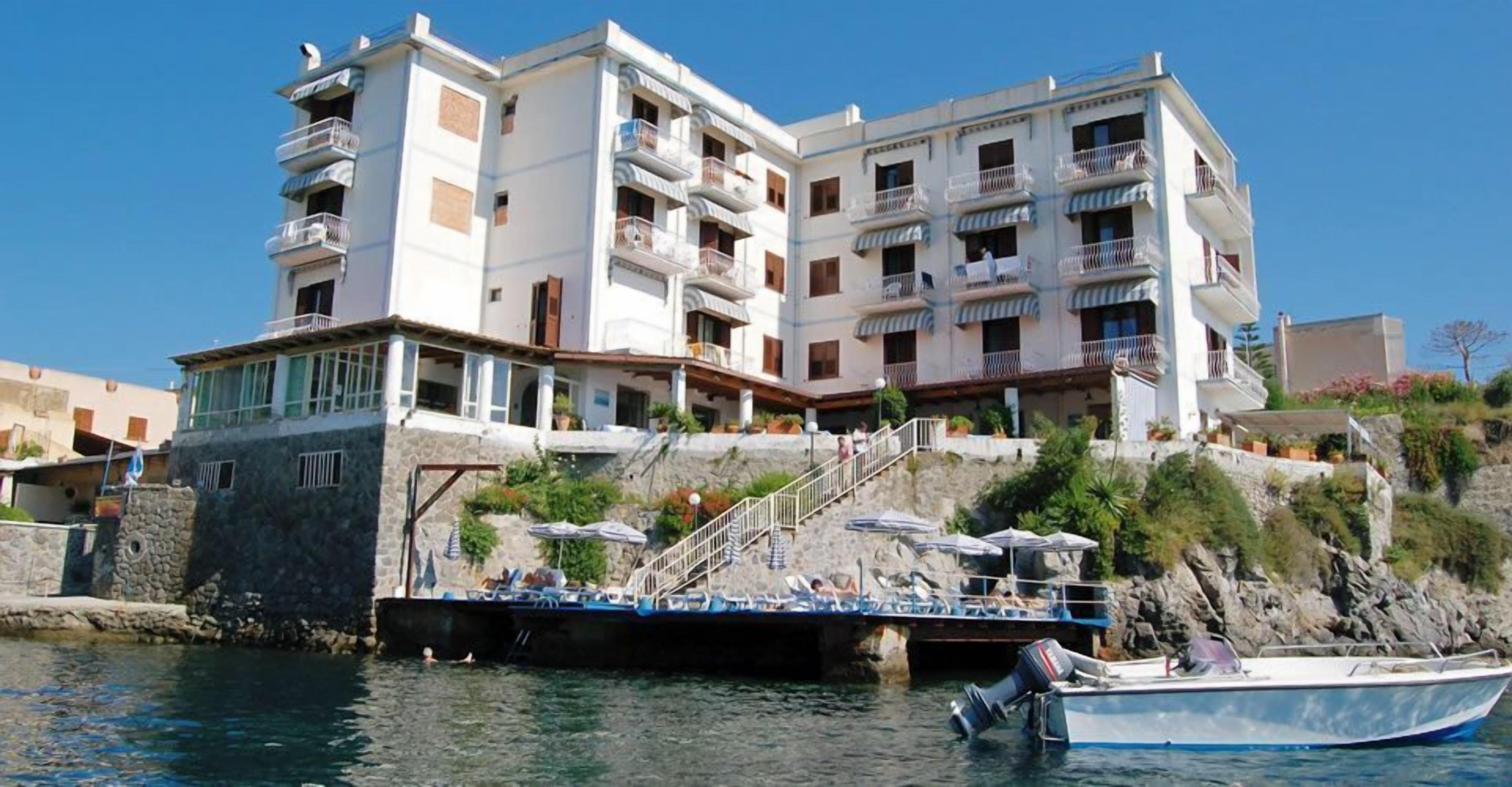 A multi-story hotel with balconies, a dock, and a boat.