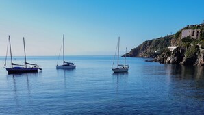 A deck with sun loungers and a railing overlooking calm waters with boats. - Rocce Azzurre (Lipari)