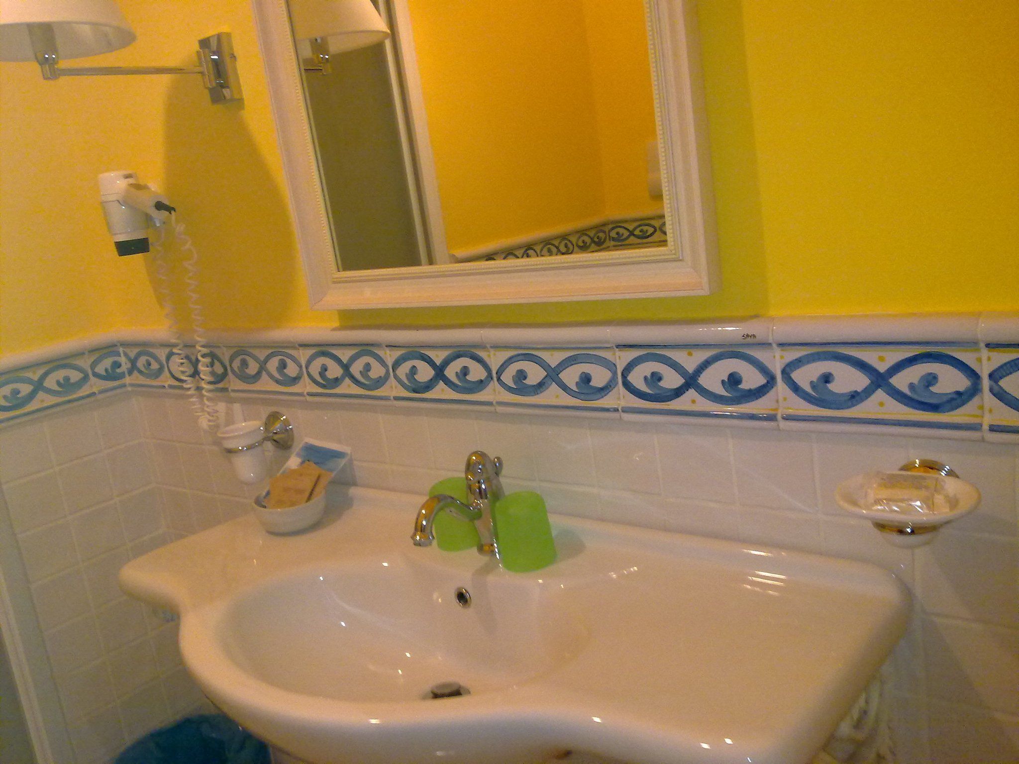 A bathroom with a white sink, green soap, and a mirror above it.