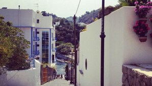 A narrow cobblestone street with a lamp post and a white building with blue trim. - Rocce Azzurre (Lipari)