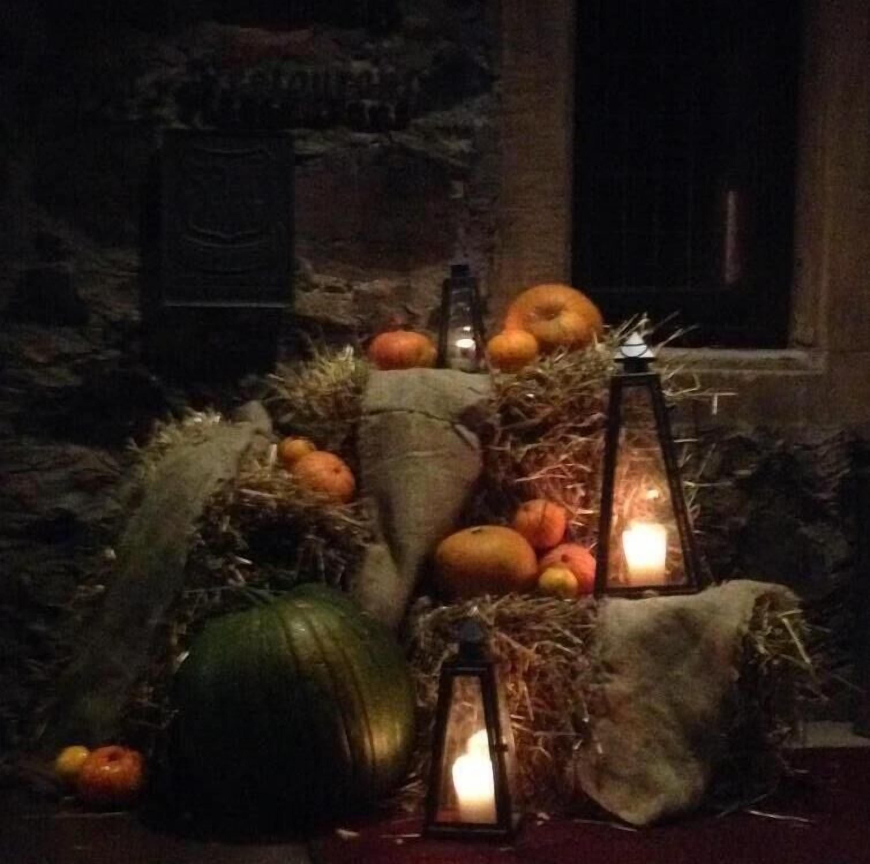 Un intérieur rustique avec un mur en pierre, une table en bois et diverses courges et potirons disposés sur de la paille.