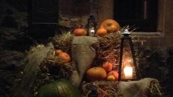 Un intérieur rustique avec un mur en pierre, une table en bois et diverses courges et potirons disposés sur de la paille.