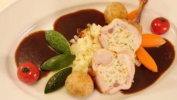 A plate of food with sliced meat, vegetables, and a sauce.