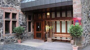 A stone building with a wooden entrance, a bench outside, and two potted plants.